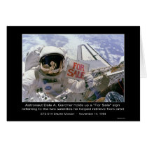 Astronaut Dale A. Gardner holds up a "For Sale" si Card