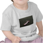 Beach pollution broken doll leg on sand shirt