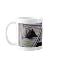 Black alpine goat doe waiting at metal gate mug