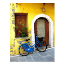 Blue bicycle against a yellow wall post cards