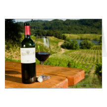 Bottle of red wine and glass on table greeting card
