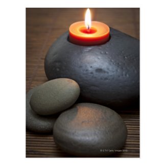 Burning candle flame with rocks in tranquil post card