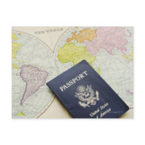 Close-up of passport lying on map postcards