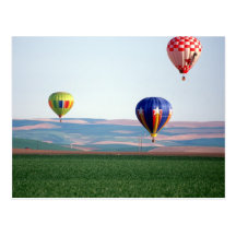 Colorful hot air balloons float over wheat postcard