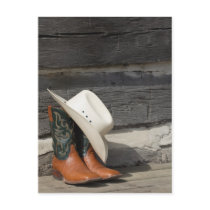 Cowboy hat on cowboy boots outside a log cabin post cards
