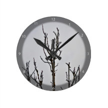 Dry Tree silhouette against cloudy sky Round Clocks