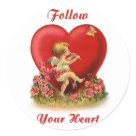 round_sticker - Cute dancing cherub is playing a flute. This musical angel has his eye on a butterfly. Flowers bloom at his feet. Big red heart in background. Text says Follow Your Heart. An adorable vintage design offered on gift items and clothing.: Sizes 