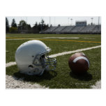 Football and football helmet on football field post cards