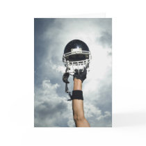 Football player holding helmet in air greeting cards