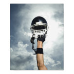 Football player holding helmet in air poster