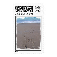 Footprints in beach sand blue ocean in back stamp