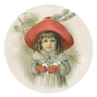 round_sticker - Sweet vintage girl is ready to play. Her arms are full of snowballs and she is wearing an elegant red hat with feathers. Pine branches accent the background.: Sizes 