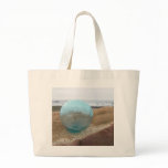 Glass float on sand at beach canvas bags