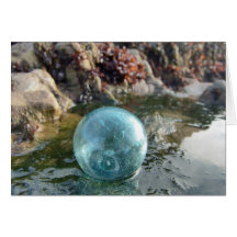 Glass Float on wet sand. Card