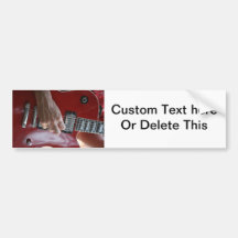Hand playing red electric guitar near pickup bumper sticker