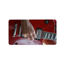 Hand playing red electric guitar near pickup custom address label