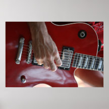 Hand playing red electric guitar near pickup posters