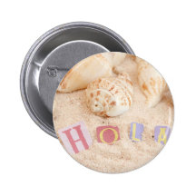 Hola, hello in Spanish on a sandy beach Buttons