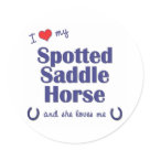 round_sticker - Show the world how much you love your Spotted Saddle Horse (and that the feeling is mutual!). With a heart and two horseshoes, the words read 'I love my Spotted Saddle Horse and she loves me'. This design is specifically for a female horse (she), we also have variants available for a male horse (he) or multiple horses (they). A perfect gift for yourself or the Spotted Saddle Horse lover in your life, this design is available on a variety of gift and apparel items!