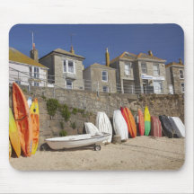 Kayaks and dinghies stacked against seawall at mousepads