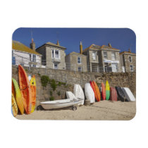 Kayaks and dinghies stacked against seawall at
