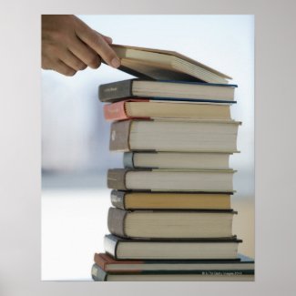 Man's hand taking a book from a stack of books poster