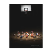 Many basketballs resting on the floor postcards