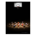 Many basketballs resting on the floor postcards