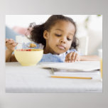 Mixed race girl reading and eating breakfast posters