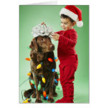 Muchacho joven que envuelve luces de navidad alred felicitaciones