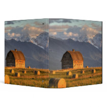 Old barn framed by hay bales and dramatic binders