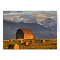 Old barn framed by hay bales and dramatic greeting card