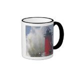 People on jetty watch large breaking waves in mugs