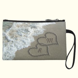 Romantic beach scene features lovely clear blue water, brown tan sand, with white waves crashing on the shore, with two interlocking hearts filled with your initials