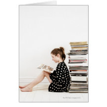 Teenage girl reading comic strip by pile of greeting card