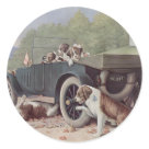round_sticker - The family outing is interrupted with a car breakdown. The pups are waiting in the car while the adult dogs lay around waiting for the repairs to be completed. One dog is under the car doing the repairs. This is a delightful vintage scene.: Sizes 