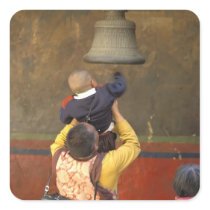 Tibetan Buddhist monk lifting a boy to ring a Sticker