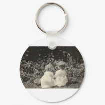 TWO ADORABLE CHILDREN SITTING BY BASKETS keychains