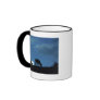 Two cows in silhouette grazing on hillside mug