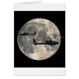 two helicopters silhouetted by a full moon