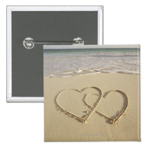 Two overlying hearts drawn on the beach with pinback button