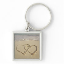 Two overlying hearts drawn on the beach with key chain