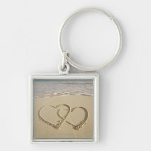 Two overlying hearts drawn on the beach with key chain