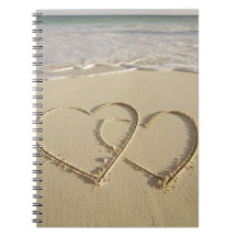 Two overlying hearts drawn on the beach with note book