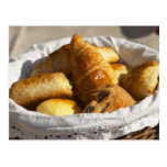 Una cesta de mimbre del desayuno con los croissant postal