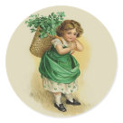round_sticker - Vintage design features a young Irish girl with a basket of Shamrocks on her back. This wee Colleen is dressed in green with shamrock patterned petticoat showing. Design has been hand retouched. Front text says... The Wearing of the Green: Sizes 