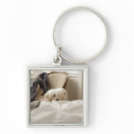 White dog hiding behind bed (differential focus) keychains