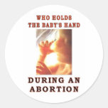 WHO HOLDS THE BABY'S HAND ROUND STICKER