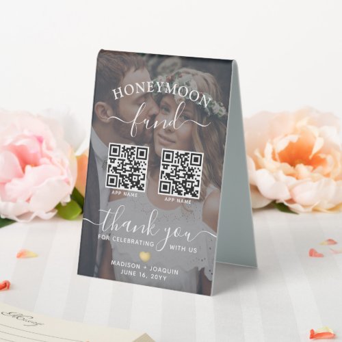 4 QR Codes 2 Photo Mobile App Honeymoon Fund Table Tent Sign - Add a personalized finishing touch to reception decorations with a stylish "honeymoon fund" wedding sign featuring your custom QR codes and photos. Guests who prefer contactless payment will appreciate the option to give a gift from their digital wallet via their smartphone or tablet. Photos and QR codes are simple to customize, and can be different or the same on front and back. (IMAGE PLACEMENT TIP: An easy way to center a photo exactly how you want is to crop it before uploading to the Zazzle website.) The two-sided black and white design features modern minimalist typography, handwritten script calligraphy, two of favorite your pictures, and up to four scannable QR codes representing your choice of contactless mobile payment apps. This elegant sign make a unique and modern addition to a special day celebration.
