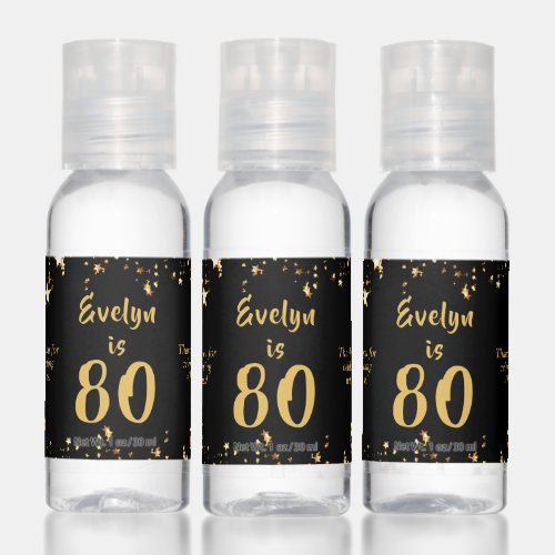 80th Birthday Modern Black Gold Stars Favor Gift Hand Sanitizer - Celebrate a 80 year old (or any age as the text is editable) and thank party guests with these personalized party favor gifts designed in an editable black background color and gold text color with gold stars. Include a personal messages on the left and/or right sides. The sample text says THANK YOU FOR CELEBRATING WITH US and duplicated on both sides but they can be different. CHANGES:  Change the colors or font style by clicking on CUSTOMIZE FURTHER. Contact the designer via Zazzle Chat or makeitaboutyoustore@gmail.com if you'd like this design modified, on another product or want coordinating items.
